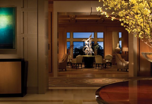 The elegant Umstead Hotel and Spa lobby features a modern art centerpiece, comfortable chairs, large windows, and warm lighting.