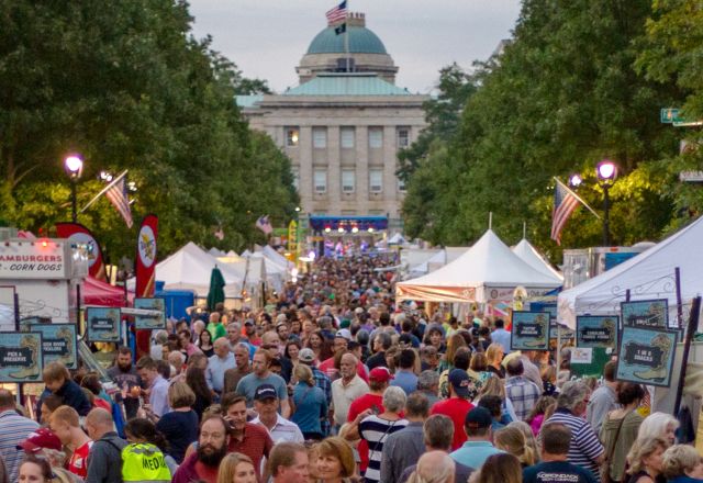 Crowds browse food and vendor tents at a downtown Raleigh festival near the North Carolina State Capitol.