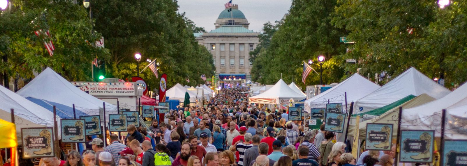 Crowds browse food and vendor tents at a downtown Raleigh festival near the North Carolina State Capitol.