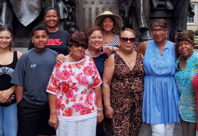 Group of adults standing together in front of a historic building in Raleigh, NC, during a reunion gathering in an outdoor setting.