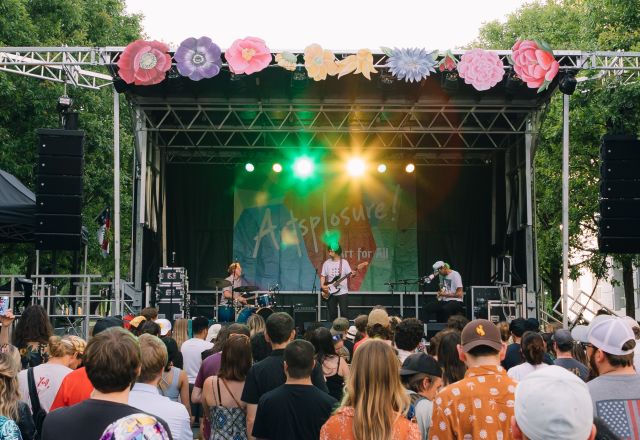 Raleigh, N.C. crowd at an outdoor weekend event with a band performing on stage.