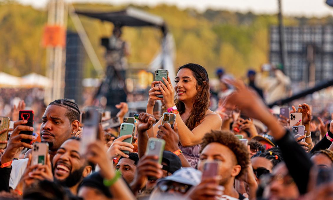 A crowd of people with smartphones taking photos or videos at a music festival.